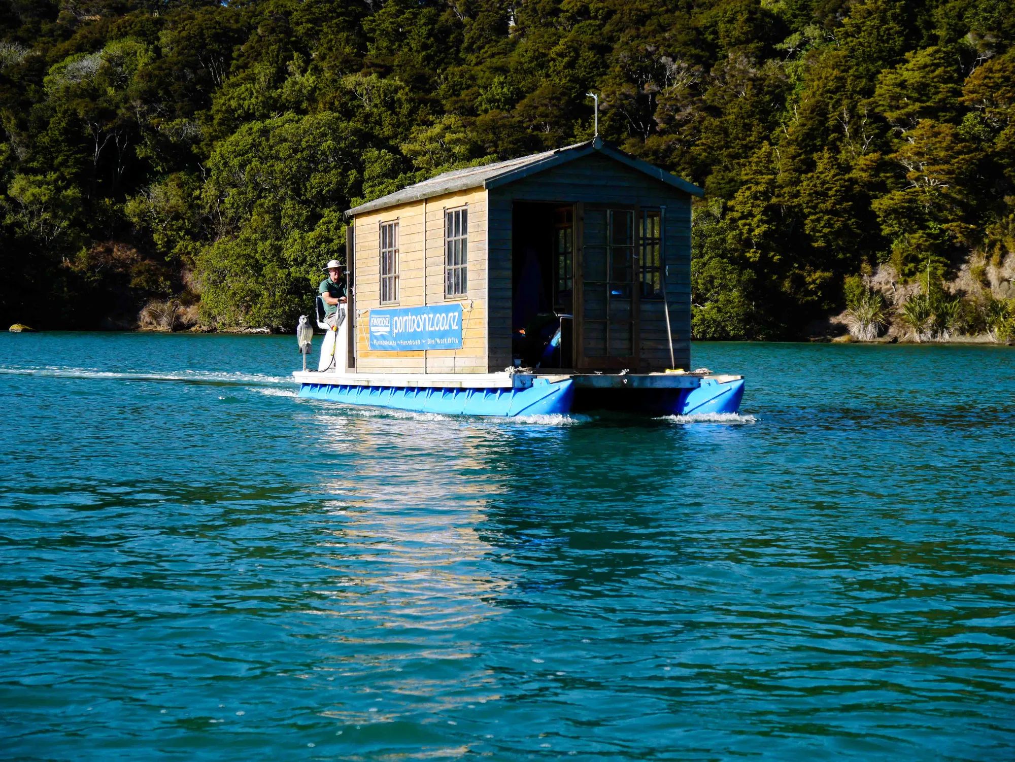 Cabin houseboat with a pontoonz.co.nz banner cruising the Sandspit estuary