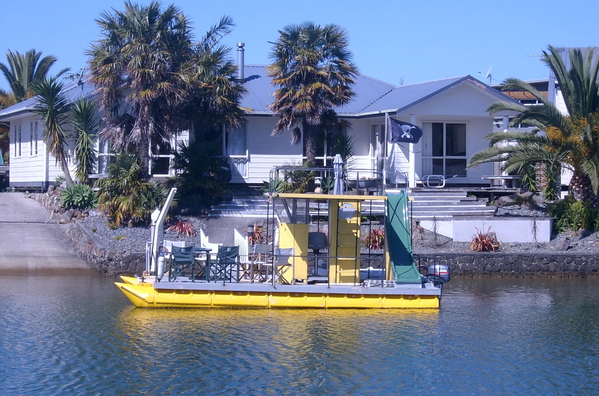 Yellow party pontoon boat moored at a waterfront home