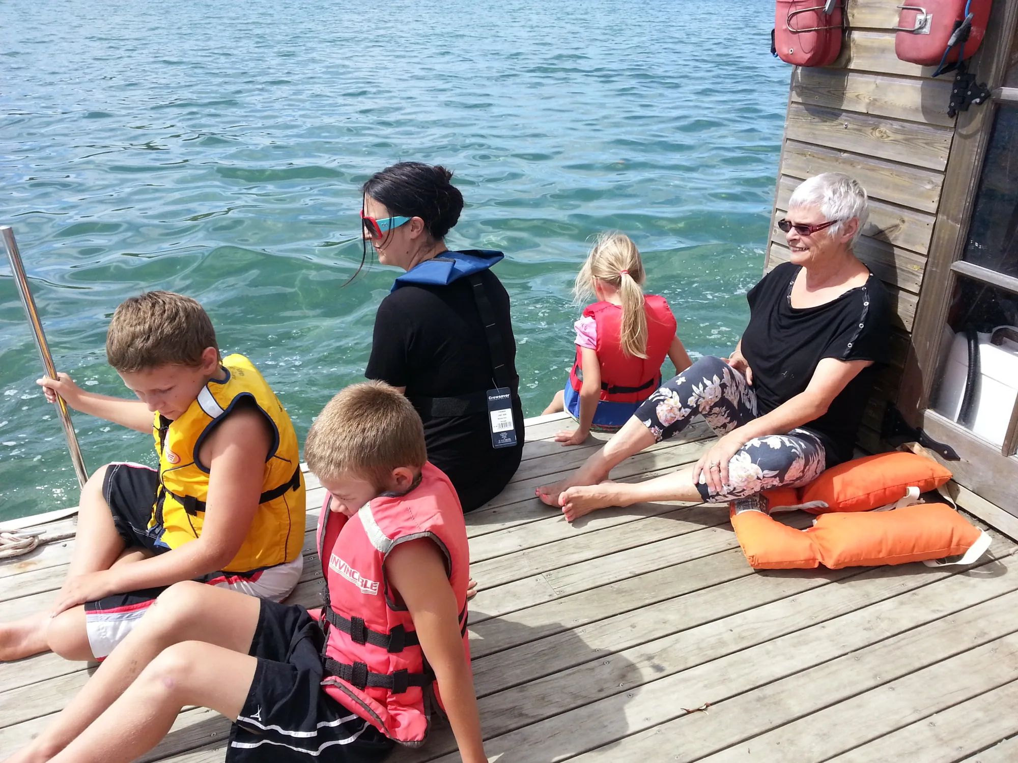 Family in life jackets relaxing on a timber pontoon deck