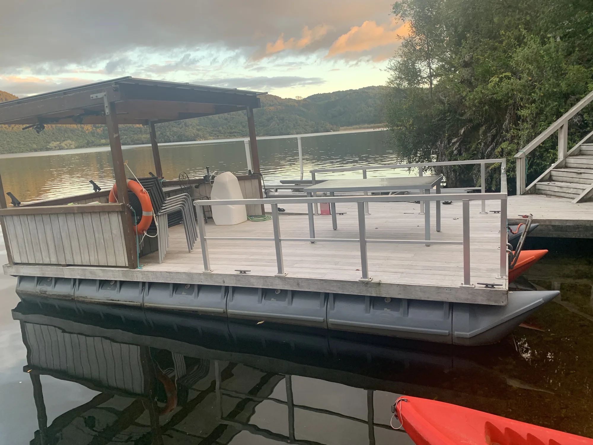 Railed deck pontoon with a shade roof moored at dusk