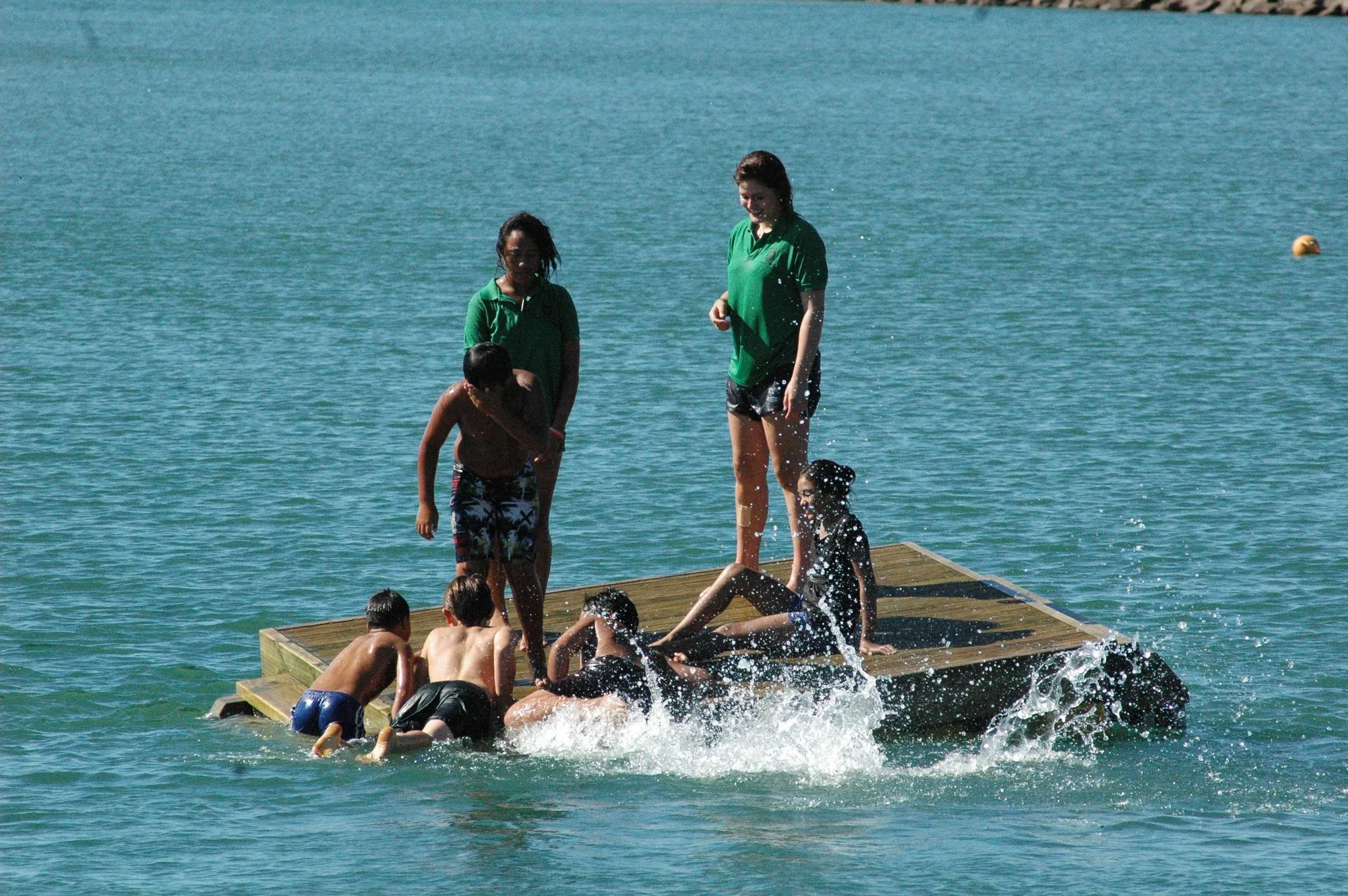 Kids climbing onto a wooden swim raft at Ōpōtiki