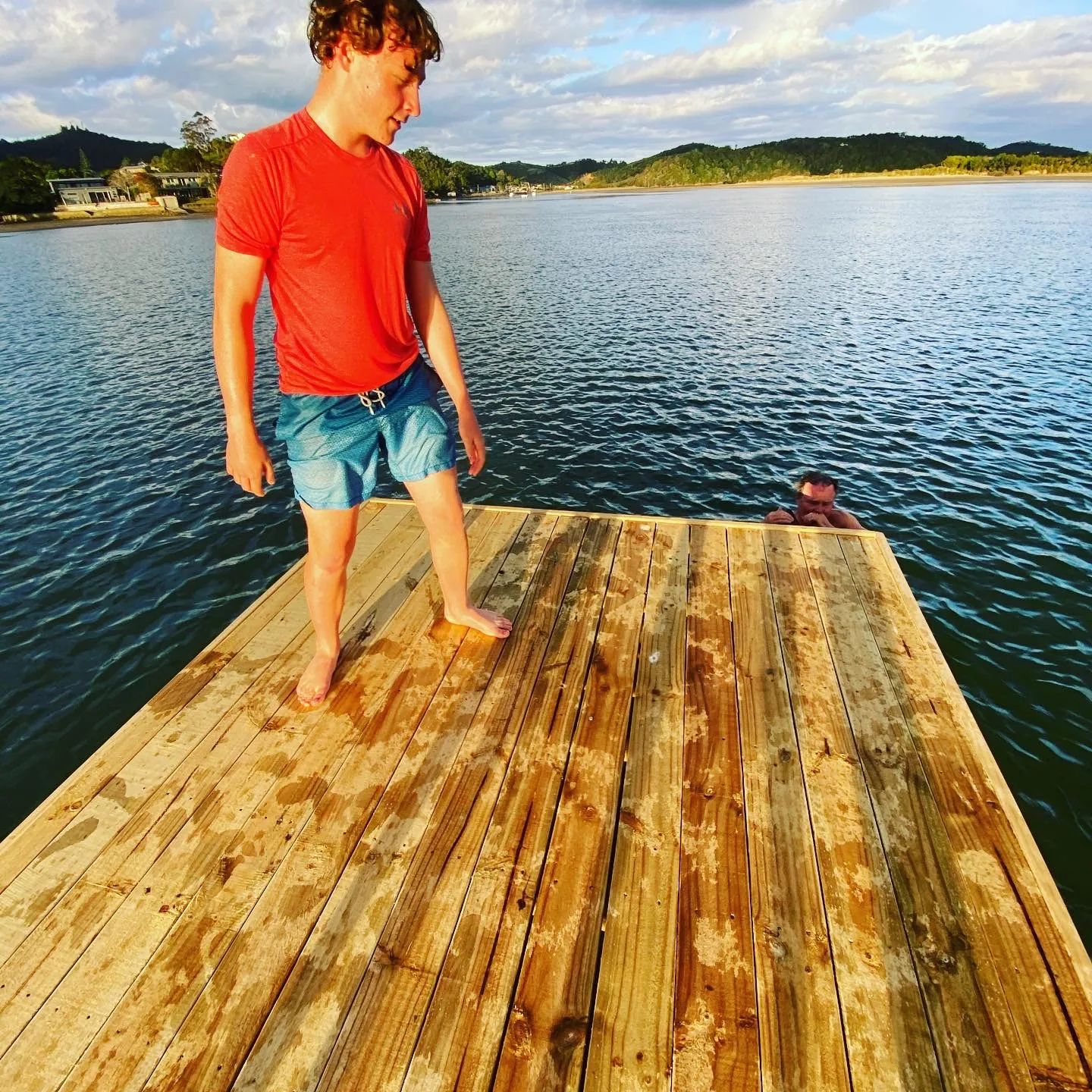 Boy standing on a timber-decked swim raft on an estuary