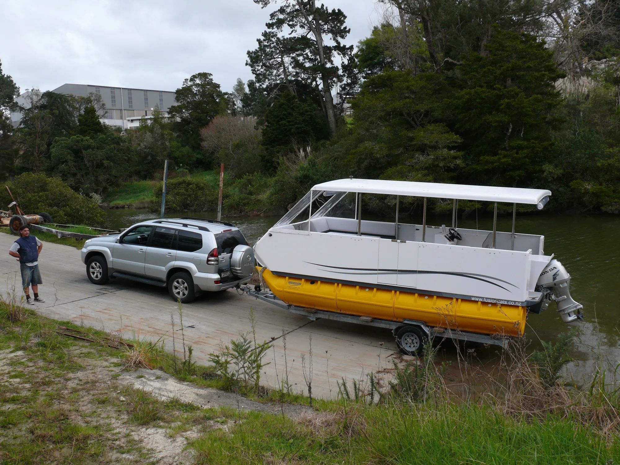 Fusion pontoon boat on a trailer behind a 4WD at a boat ramp