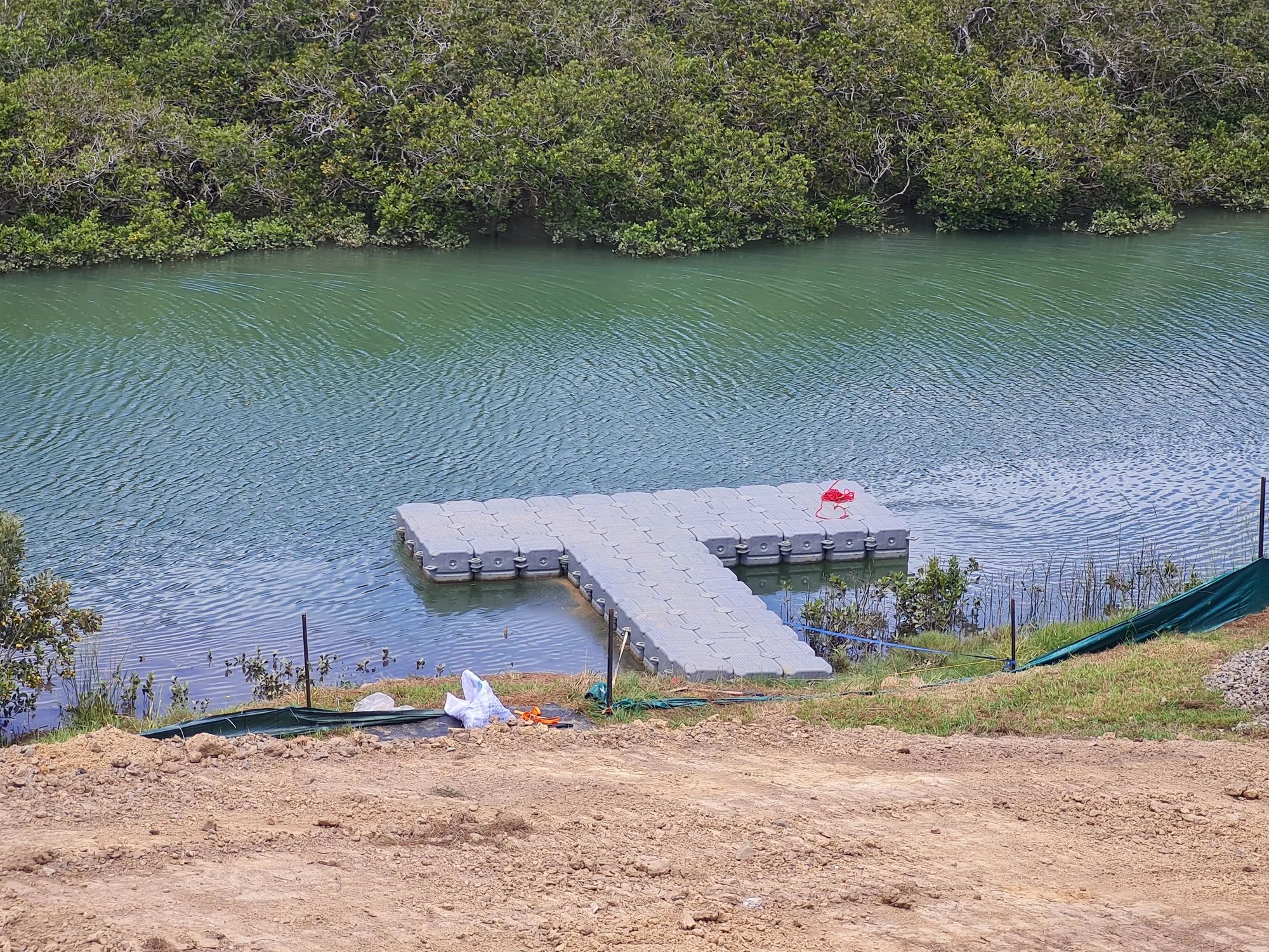 T-shaped modular floating jetty on an estuary, bush behind