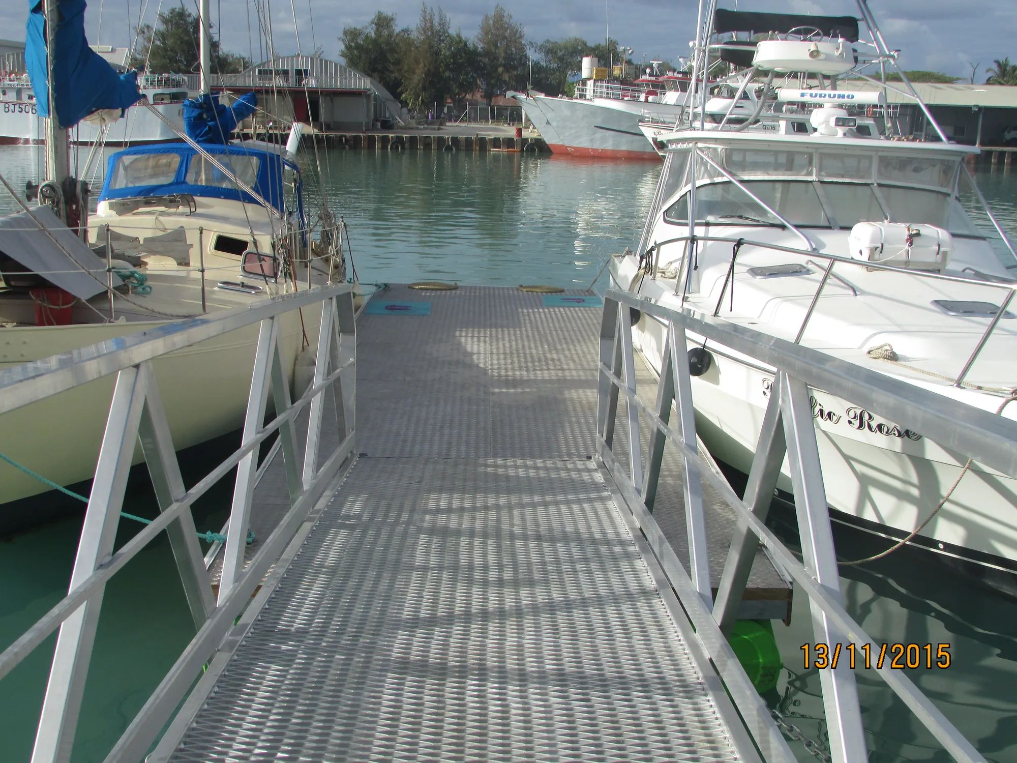 Aluminium gangway leading down to a marina berth between boats
