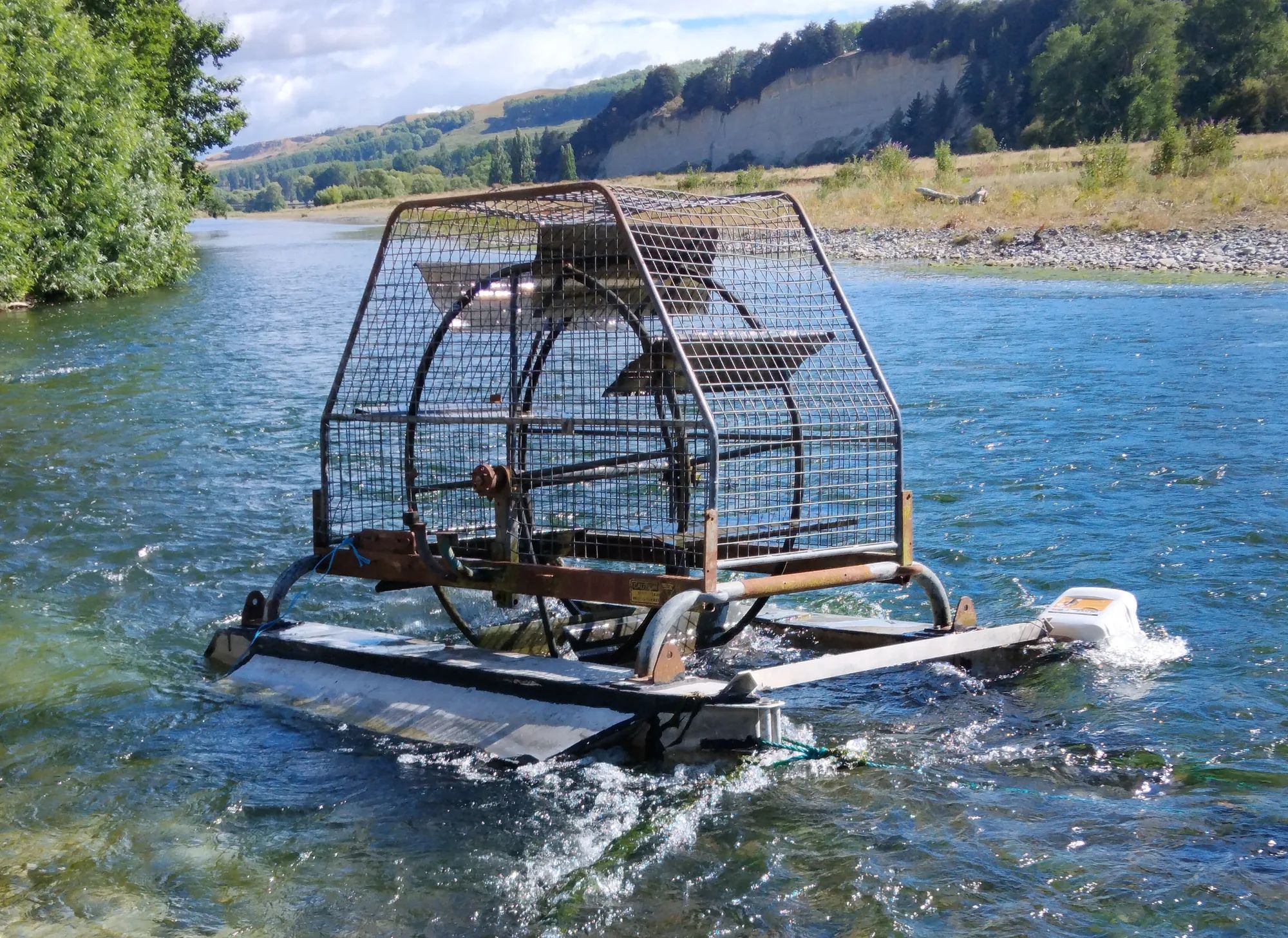 Caged waterwheel mounted on a floating pontoon in a river