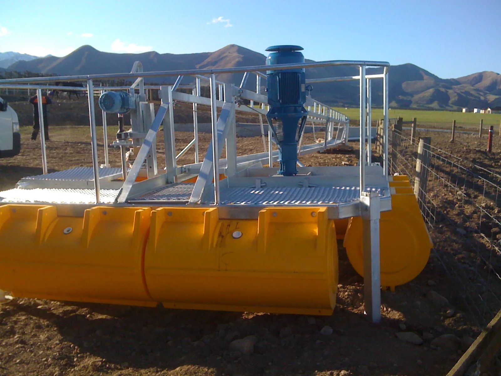 Railed pump platform on yellow pods, mountains behind