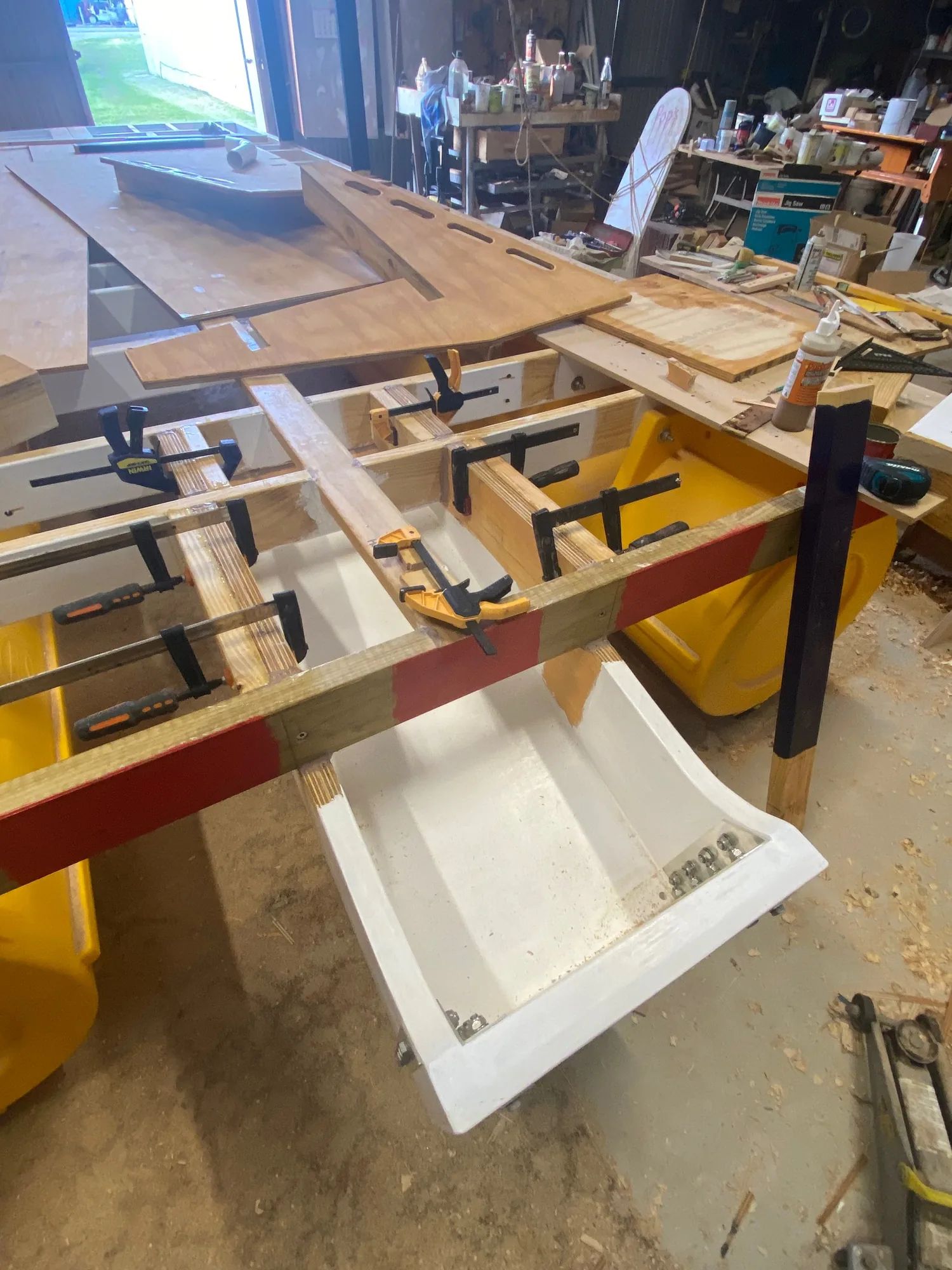 Boat frame clamped up on yellow pods in a workshop
