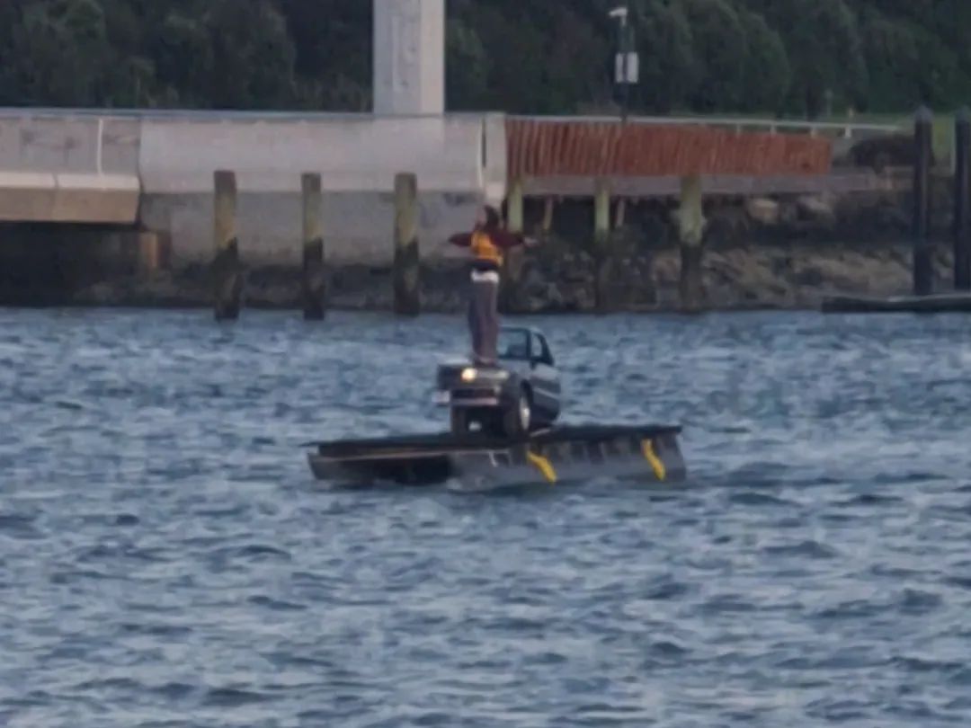 Video: pod barge carrying a car, with a crew member standing on the roof