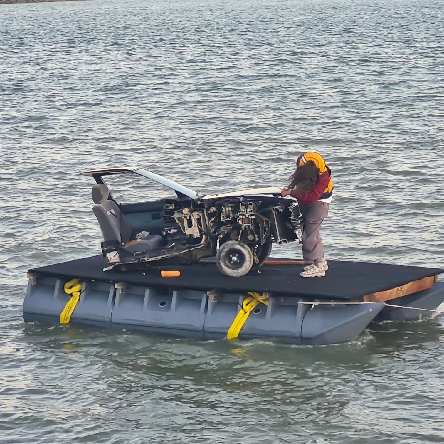 Cut-away car rig strapped to a pod barge on open water