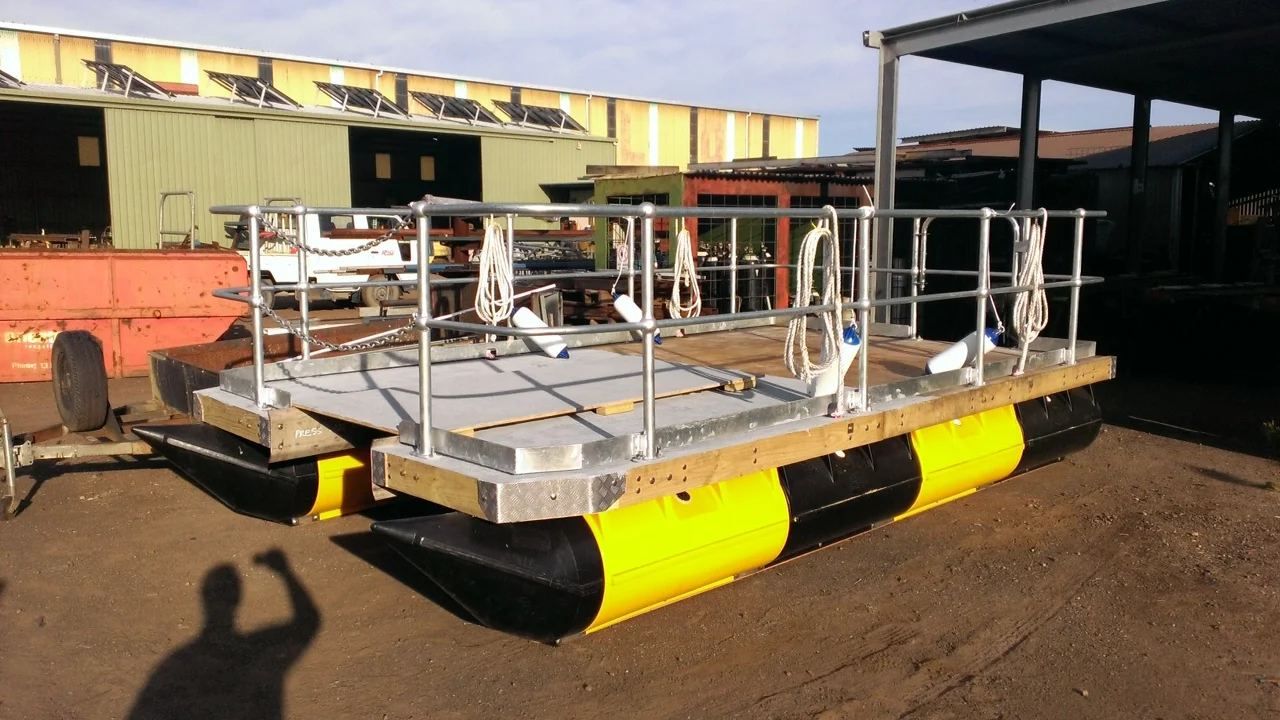 Work barge on yellow and black pods with steel railings